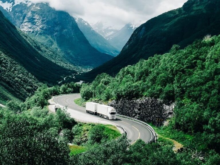 AI-generated image of a white truck driving on a highway through lush green mountains