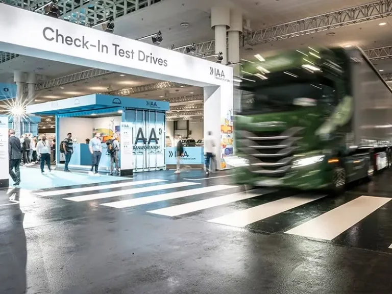 Check-in Test Drives booth at Hanover IAA Transportation Fair with a green truck passing by