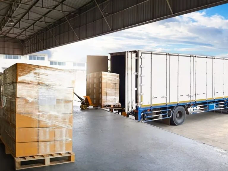 long white truck for cargo transport is being loaded with wooden crates