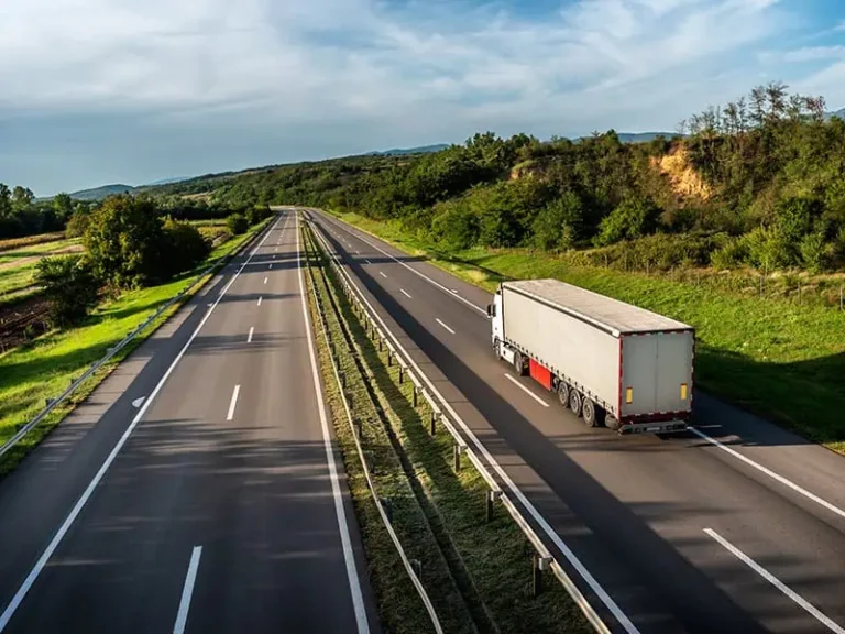 White truck driving on a road through lush green nature, representing the future of road transport